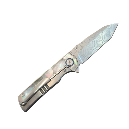 Vorixn Forest Mirage flipper knife open on clip side with Damascus blade angled 45 degrees upward, titanium handle with mother of pearl inlay