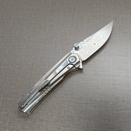 VORIXN Ocean Mirage folding knife open, pocket clip side, Damascus blade angled 45 degrees upward