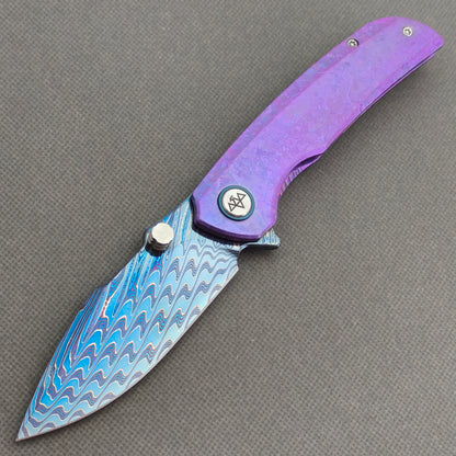 VORIXN Rimeforge KB125 Folding Knife – open non-clip side view showing crystallized titanium handle and Damascus blade profile.