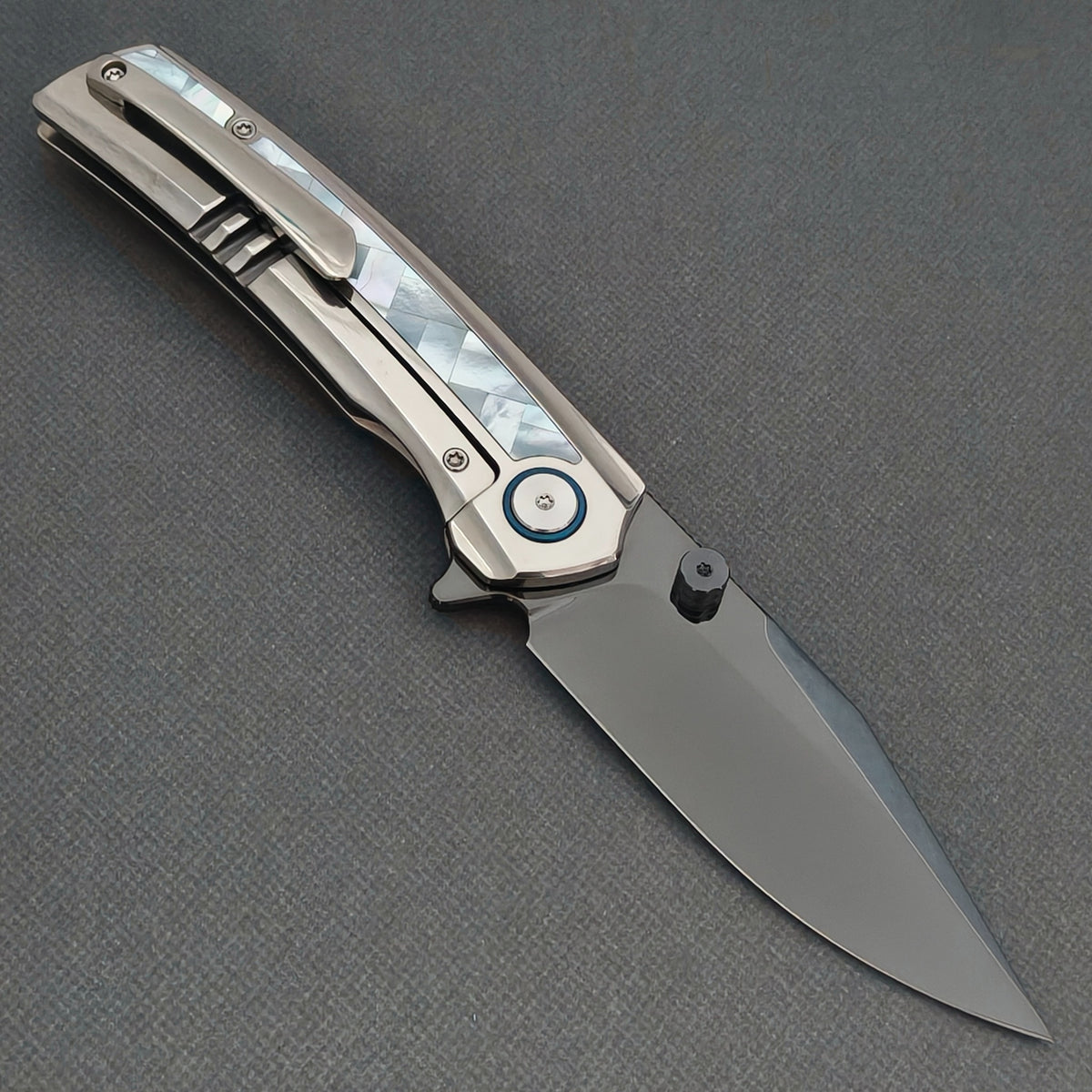 VORIXN Ocean Mirage KB093 folding knife, open pocket clip side showing a dark blade, white handle inlay and blue pivot ring.