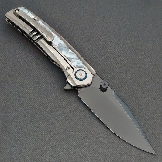 VORIXN Ocean Mirage KB093 folding knife, open pocket clip side showing a dark blade, white handle inlay and blue pivot ring.