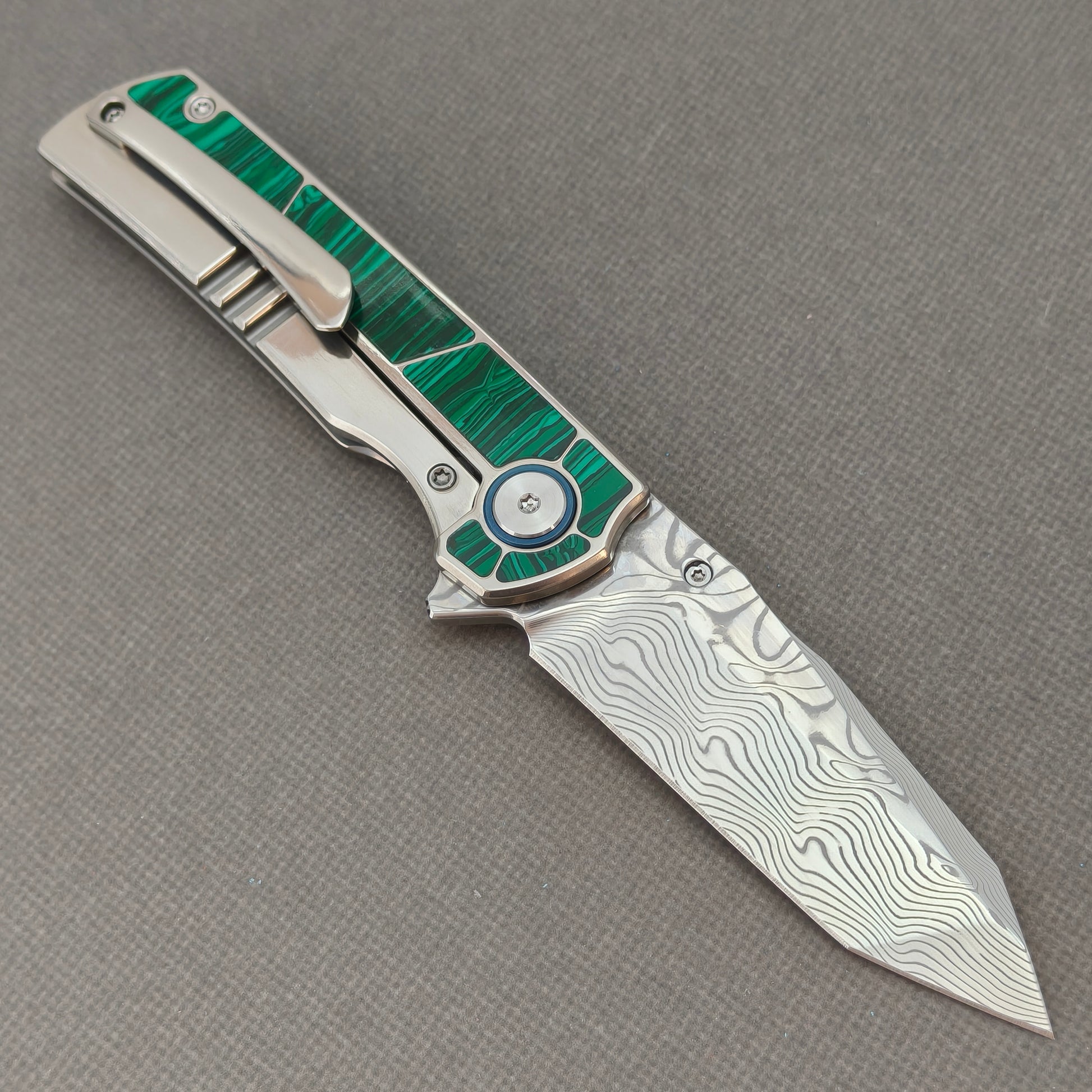 VORIXN KB062 open clip-side view showing pocket clip, malachite inlaid titanium handle, and overall profile.