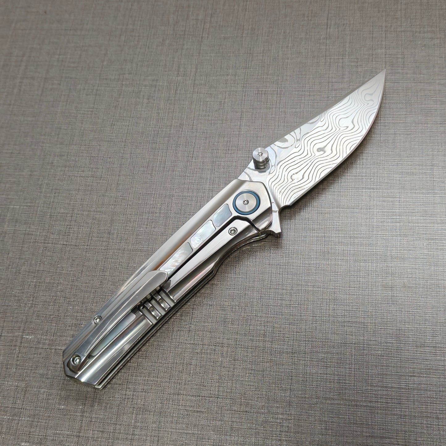 VORIXN Ocean Mirage folding knife open, pocket clip side, Damascus blade angled 45 degrees upward