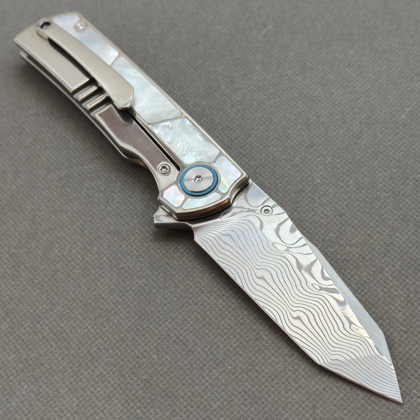 VORIXN KB063 open clip-side view showing pocket clip, white mother-of-pearl inlaid titanium handle, and overall profile.