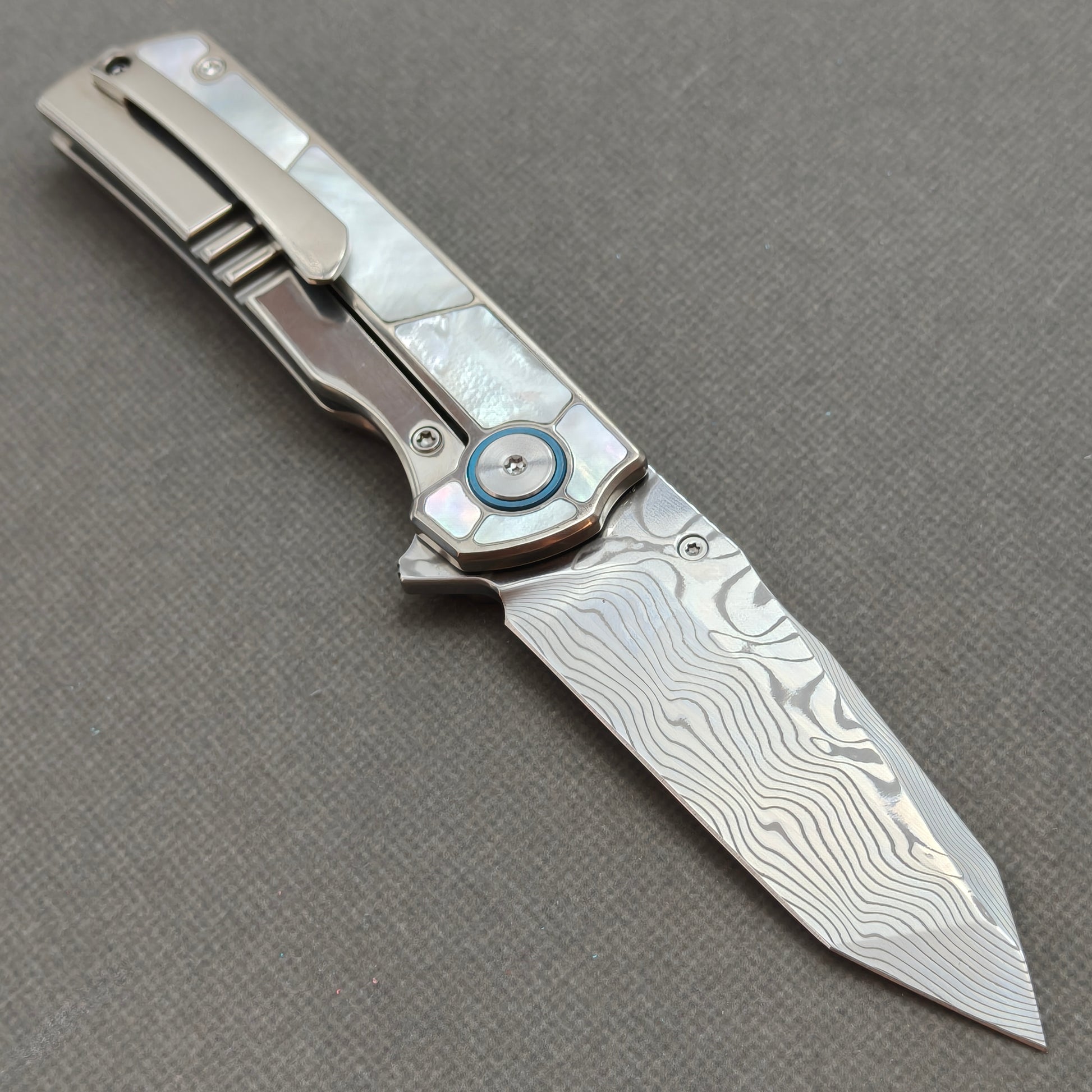 VORIXN KB063 open clip-side view showing pocket clip, white mother-of-pearl inlaid titanium handle, and overall profile.