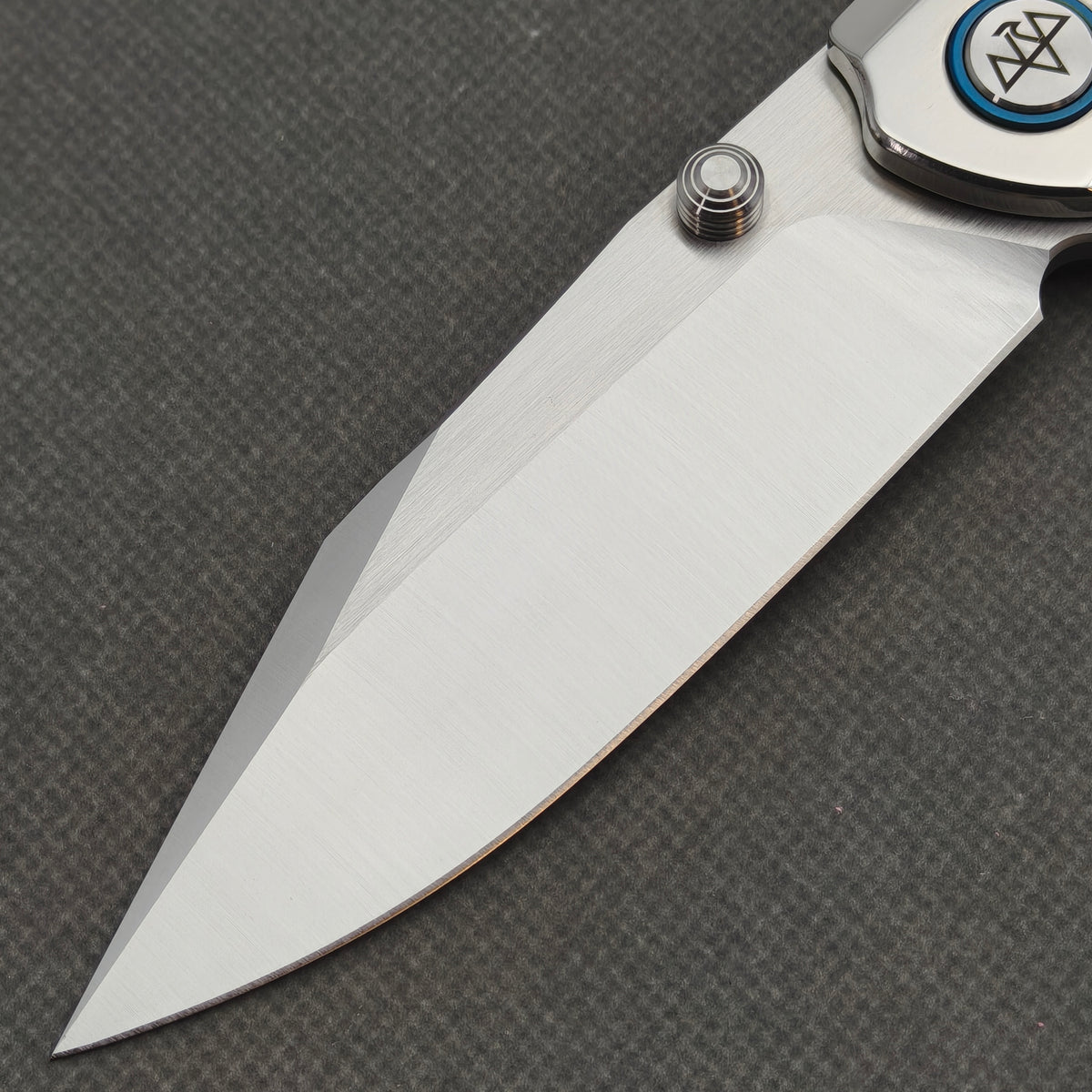 Close-up of the VORIXN Pearlglint KB159 blade, grooved thumb stud and logo pivot with a blue ring.