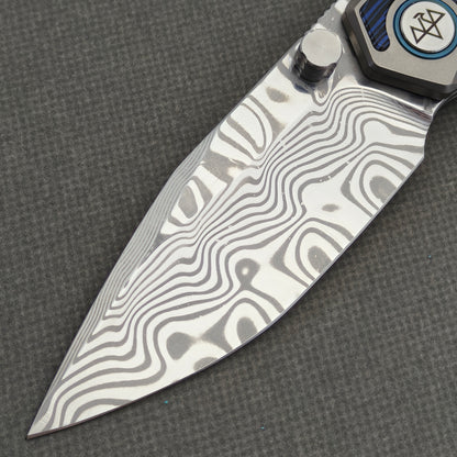 VORIXN Tidecipher KB157 Folding Knife – blade detail showing flowing Damascus patterns, cutting edge, and thumb stud.