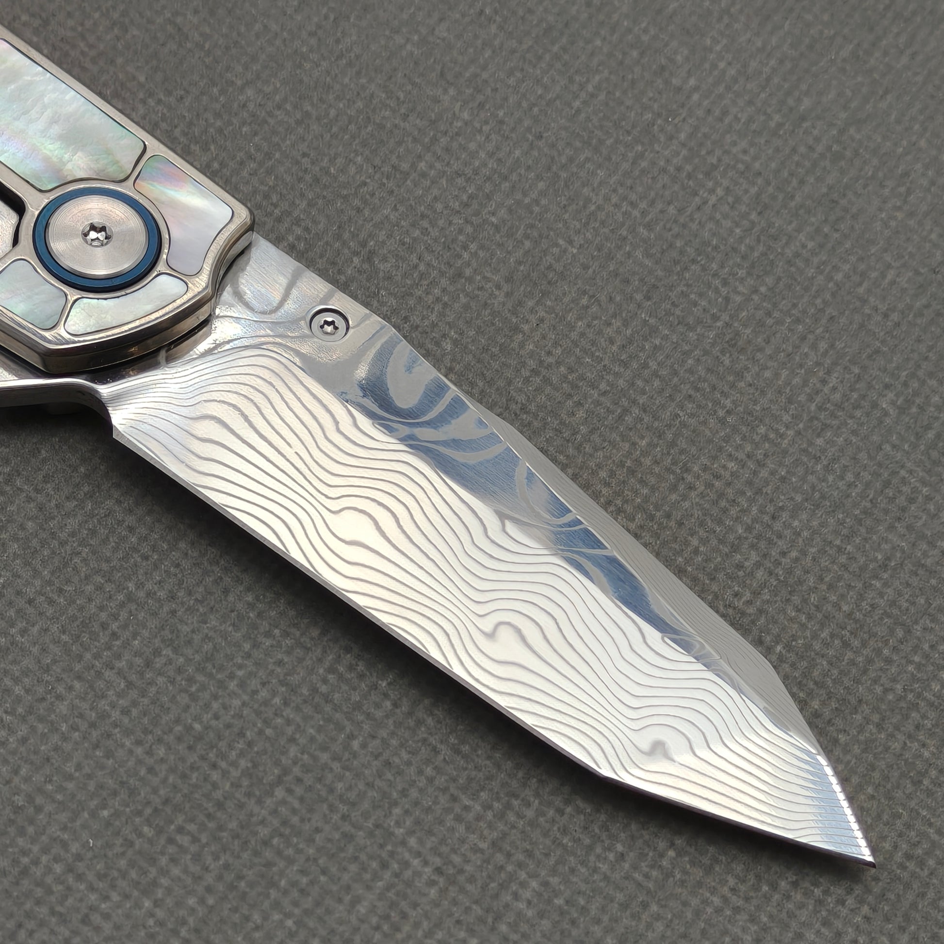 VORIXN KB059 clip-side blade detail showing the Damascus blade pattern.