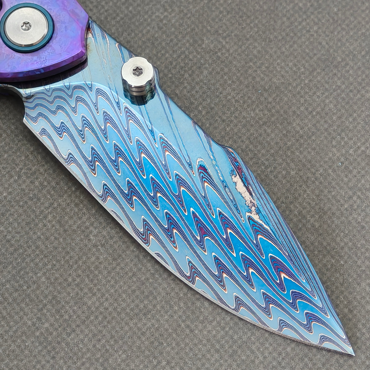 VORIXN Rimeforge KB125 Folding Knife – clip side blade detail showing Damascus steel and crystallized titanium handle junction.