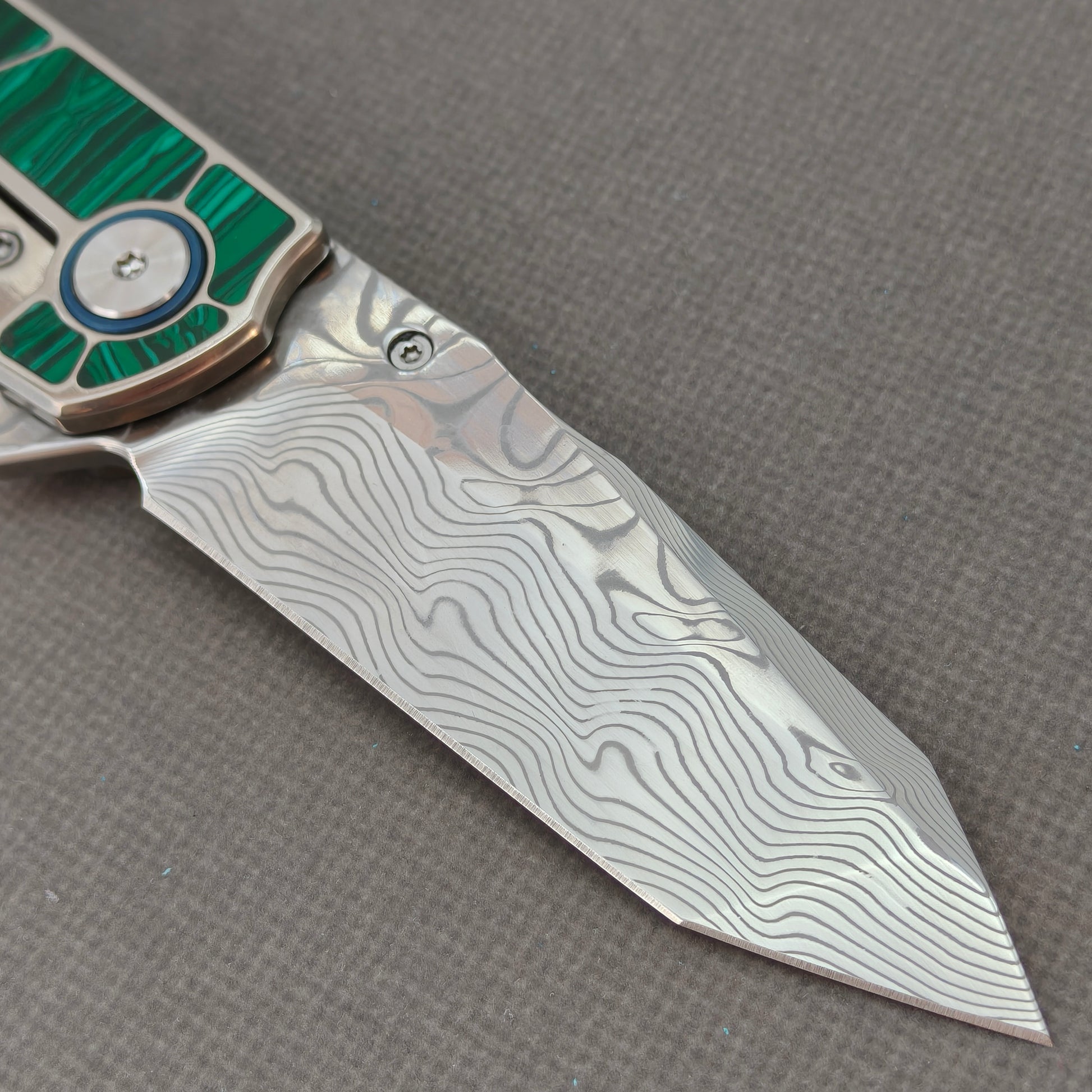 VORIXN KB062 clip-side blade detail showing the Damascus blade pattern.