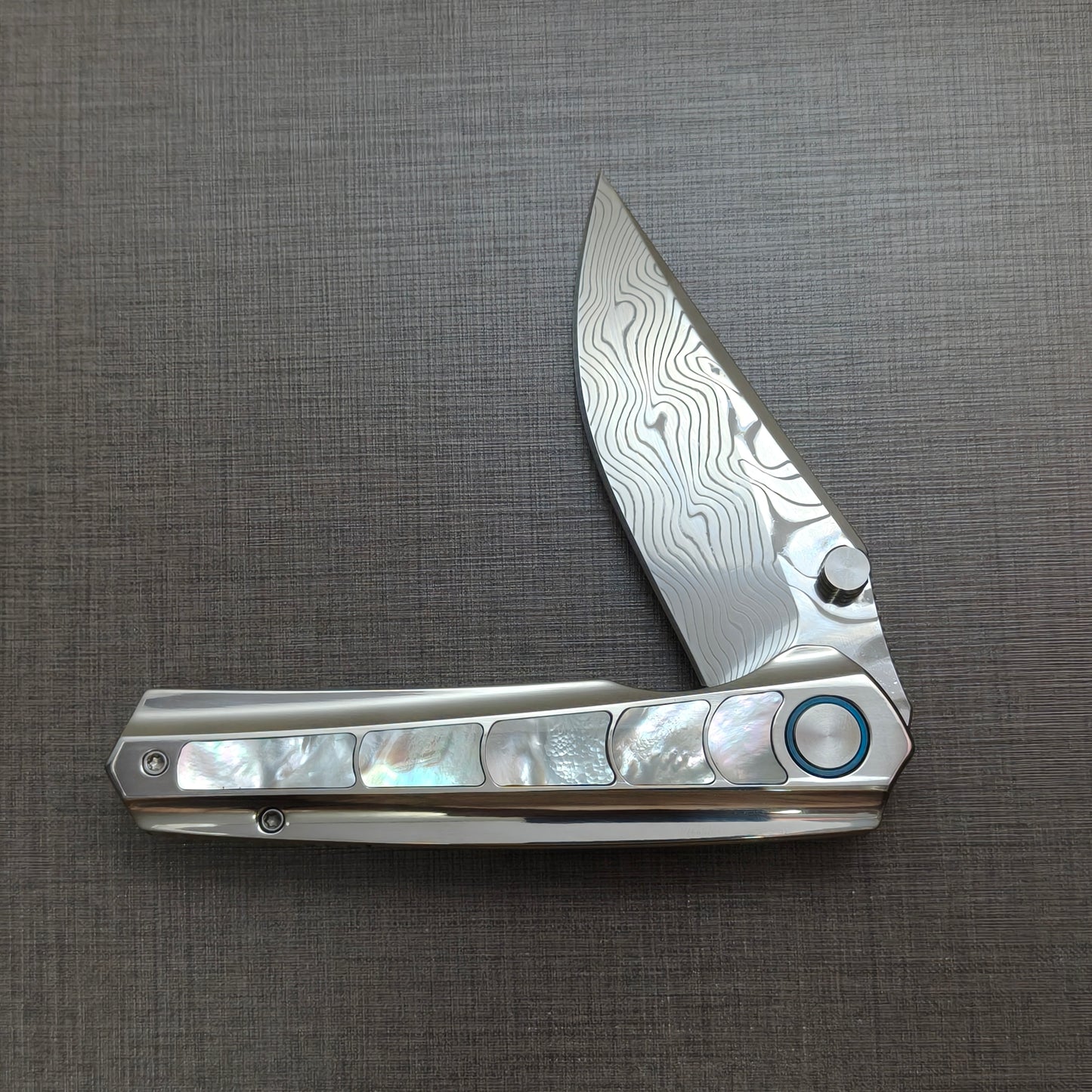 VORIXN Ocean Mirage folding knife half open, non-clip side, titanium handle shown horizontally