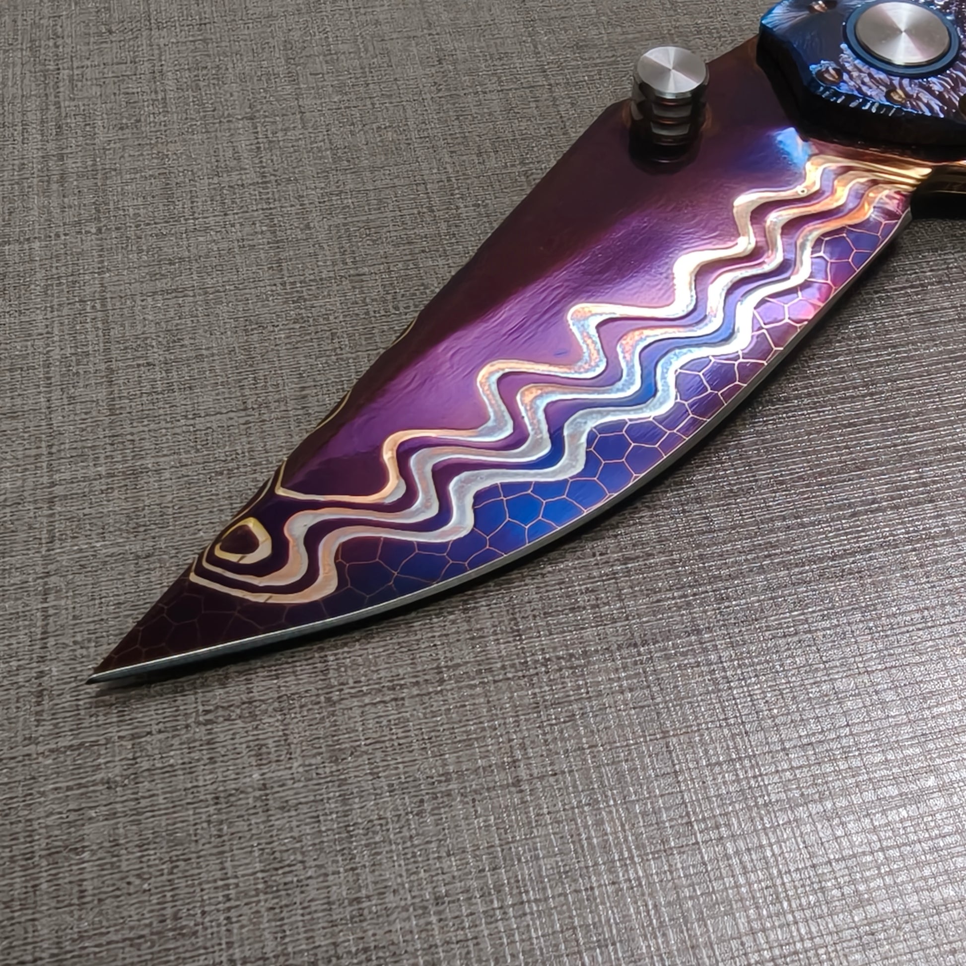 Close-up detail of the VORIXN Impact Origin folding knife blade with hand-flame Dragon Scale Damascus pattern