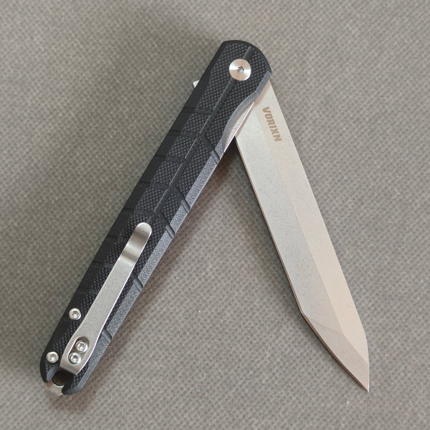 VORIXN KM001 partially open folding knife showing flipper, pivot, and carbon fiber handle profile.