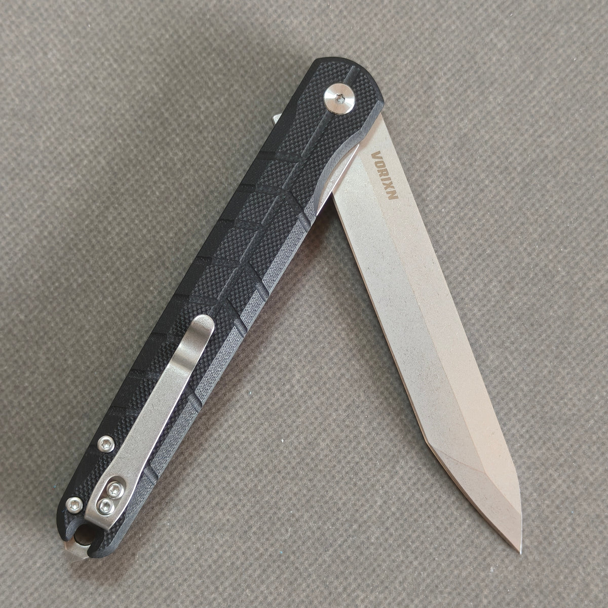 VORIXN KM001 partially open folding knife showing flipper, pivot, and carbon fiber handle profile.