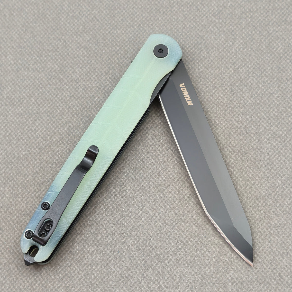 VORIXN KM004 partially open folding knife showing flipper, pivot, and carbon fiber handle profile.