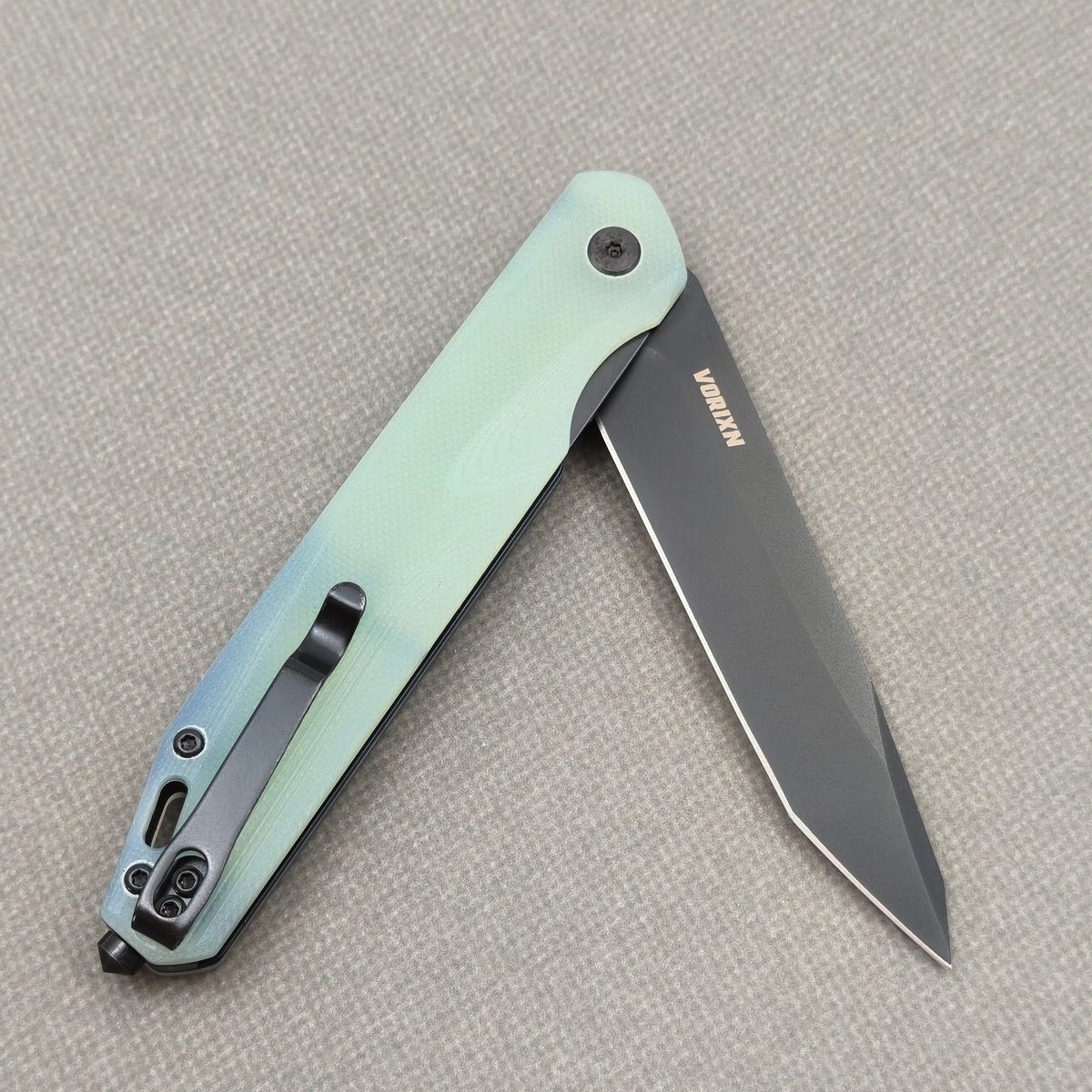 VORIXN KM005 partially open folding knife showing flipper, pivot, and carbon fiber handle profile.