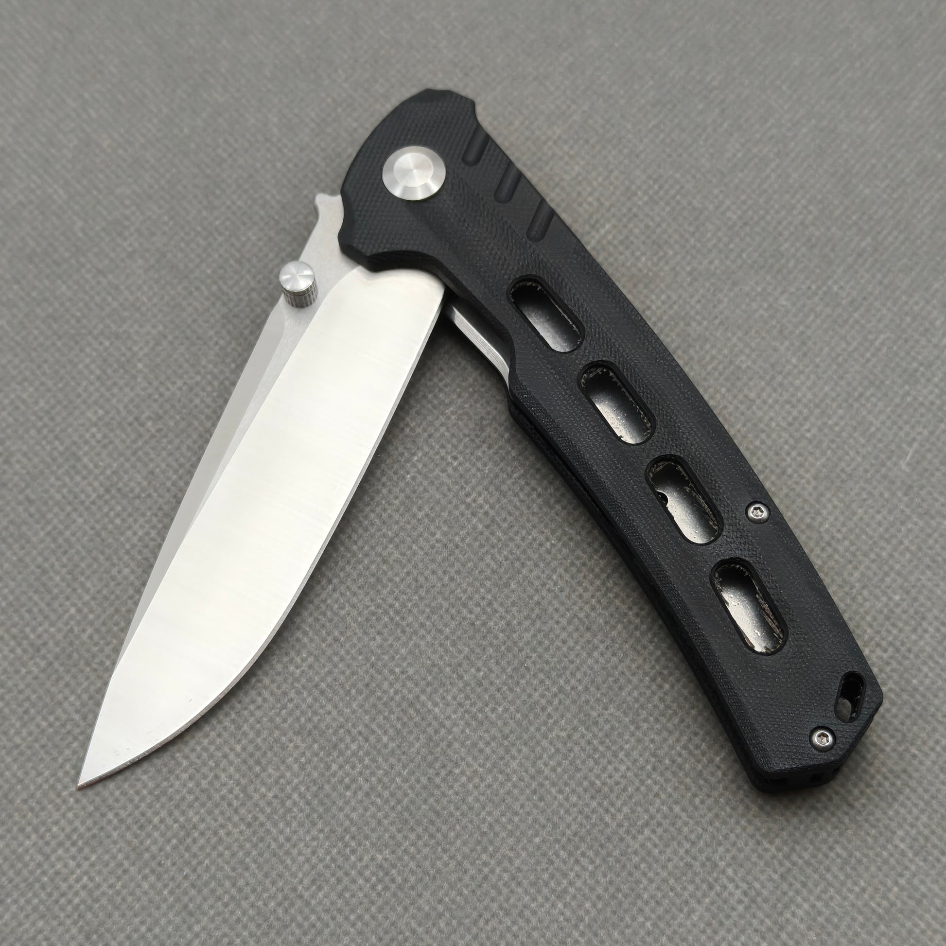 VORIXN KA001 partially open pocket knife showing flipper, thumb stud, pivot, and G10 handle profile.