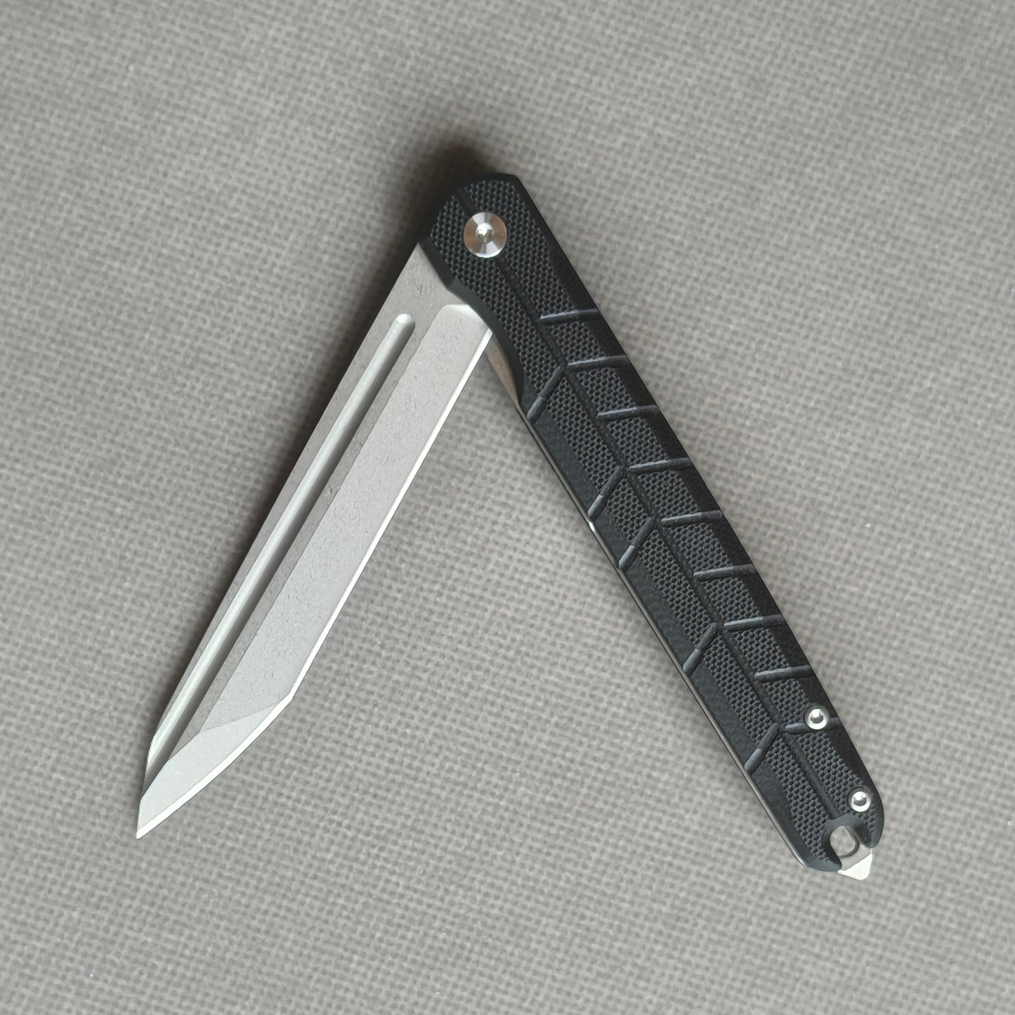 VORIXN KM001 partially open folding knife showing flipper, pivot, and carbon fiber handle profile.