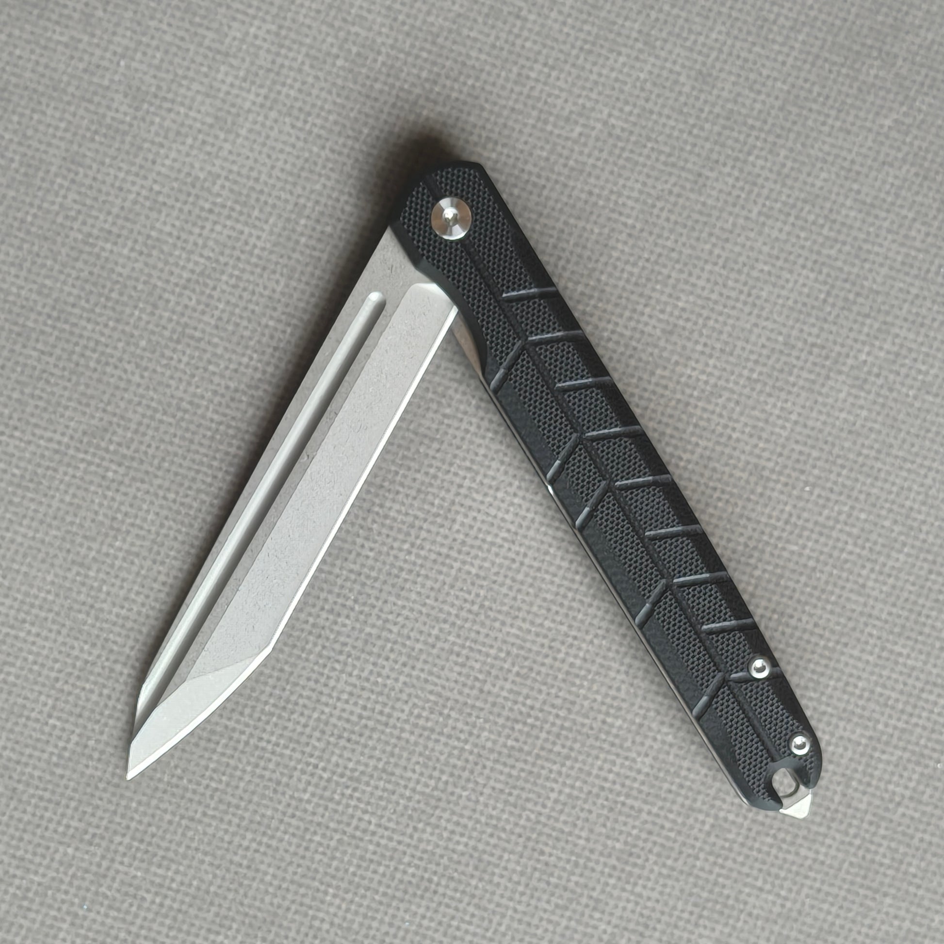 VORIXN KM001 partially open folding knife showing flipper, pivot, and carbon fiber handle profile.