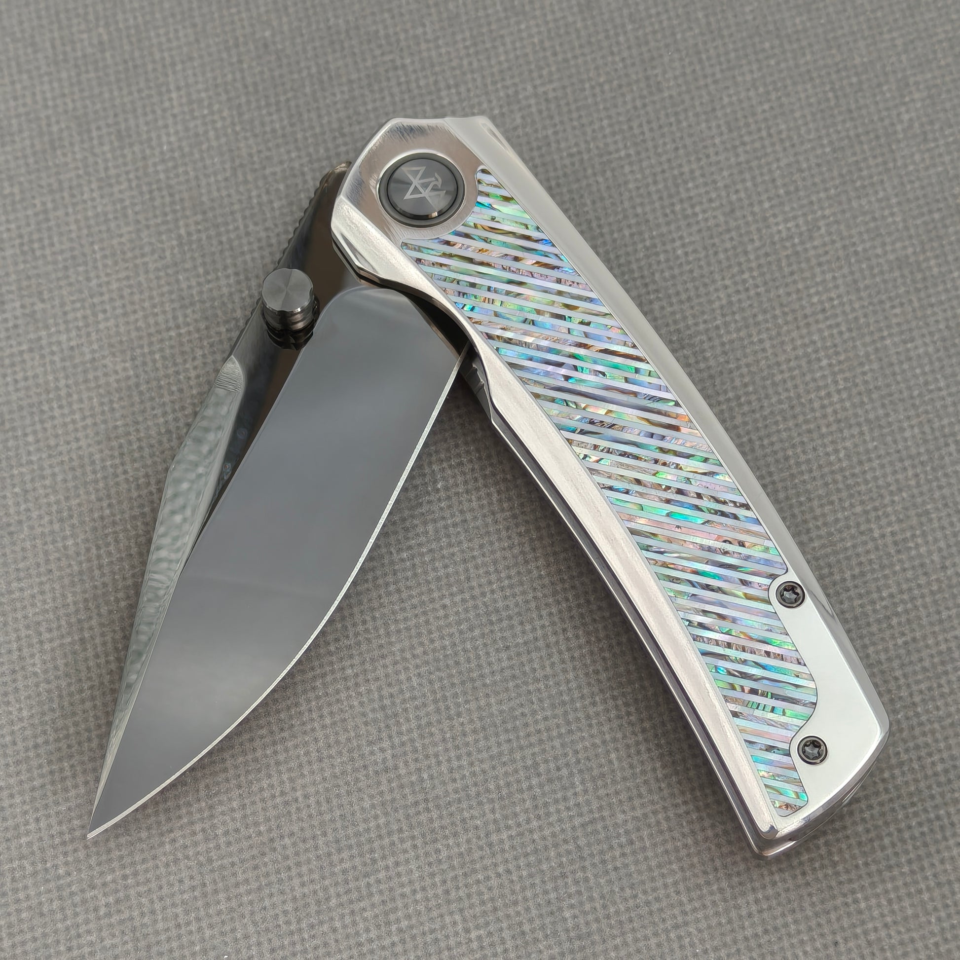 VORIXN KB103 Ocean Mirage Folding Knife – partially open EDC view showing flipper, thumb stud, pivot, and Iridescent Mother-of-Pearl Inlaid Titanium handle profile