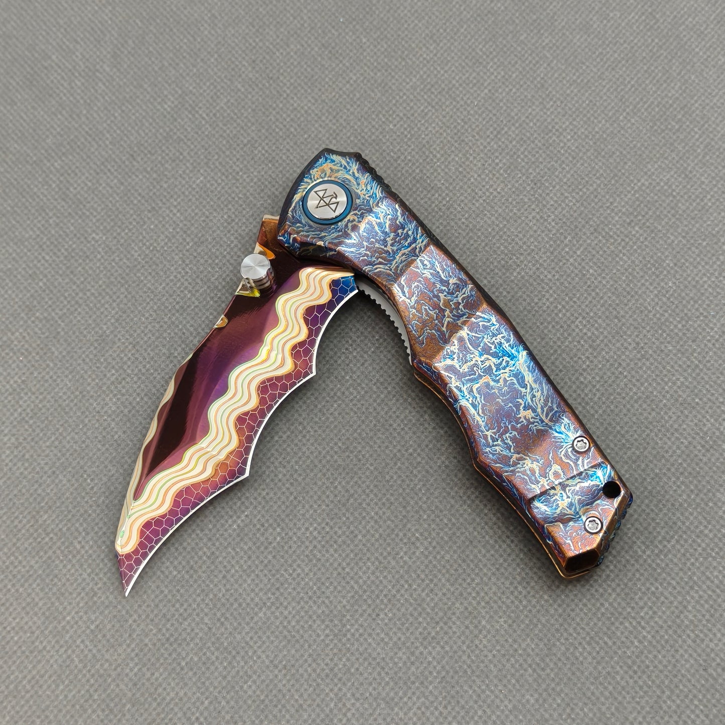VORIXN KB057 partially open EDC folding knife showing flipper, thumb stud, pivot, and flamed titanium handle profile.