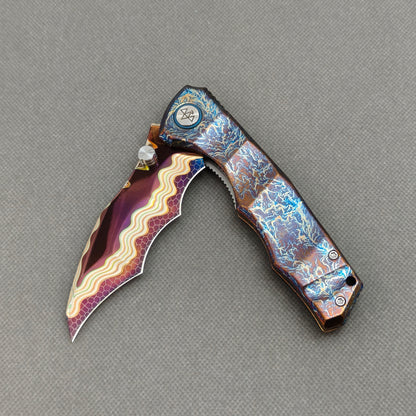 VORIXN KB057 partially open EDC folding knife showing flipper, thumb stud, pivot, and flamed titanium handle profile.