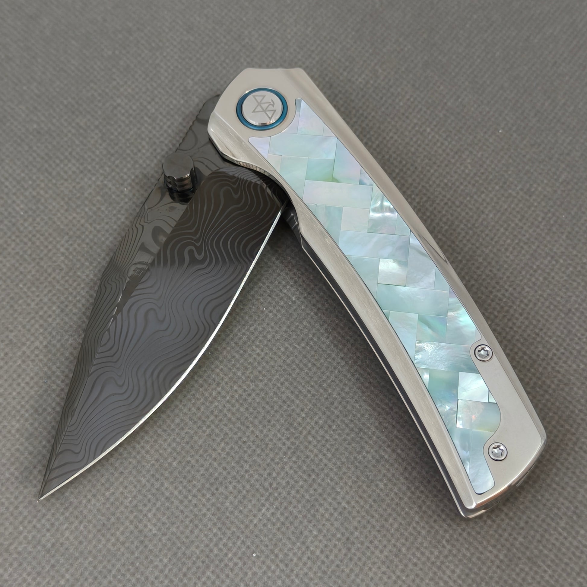 VORIXN KB104 Ocean Mirage Folding Knife – partially open EDC view showing flipper, thumb stud, pivot, and Mother-of-Pearl Inlaid Titanium handle profile