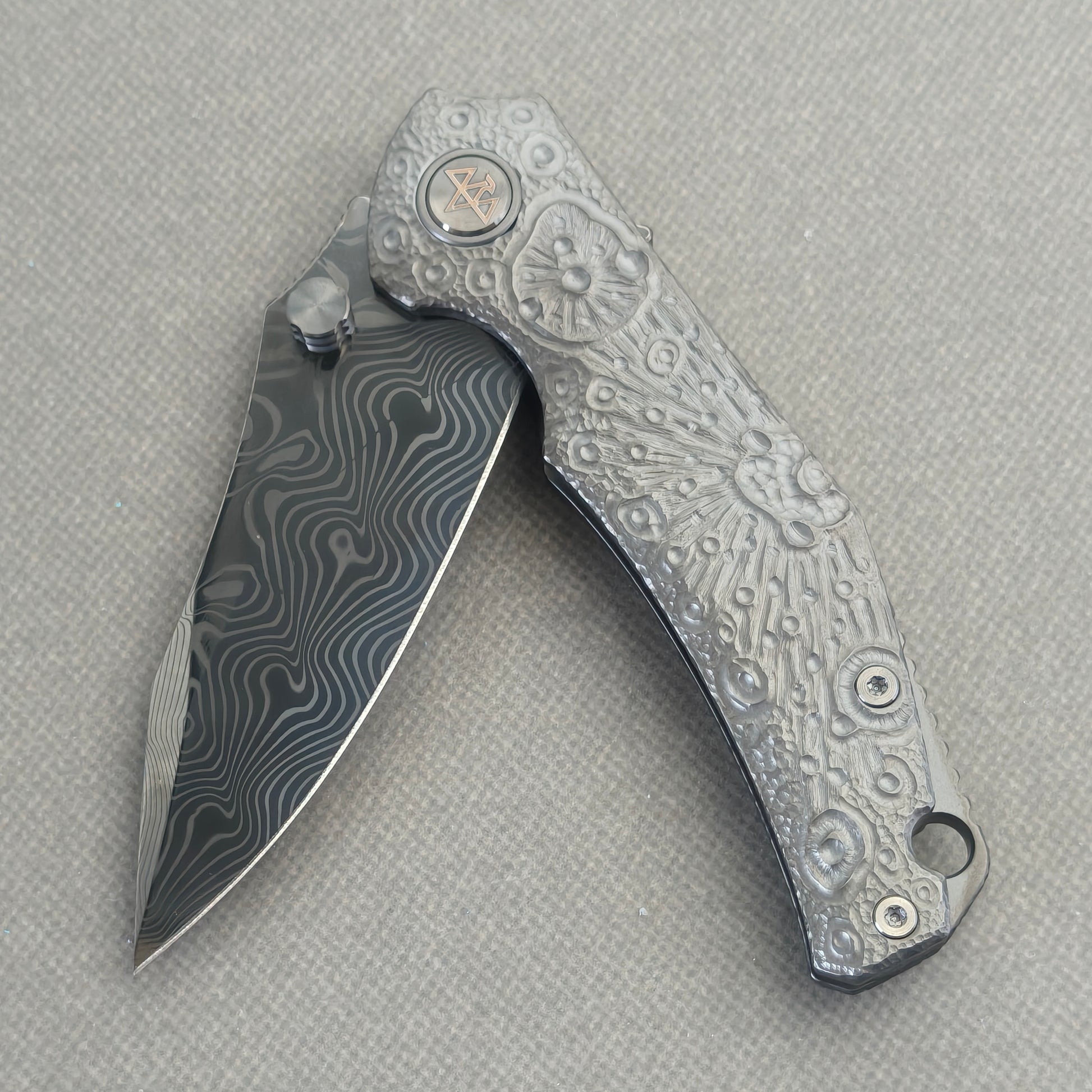VORIXN Prism KB129 Folding Knife – partially open EDC view showing flipper, thumb stud, pivot, and hand-engraved anodized titanium handle profile