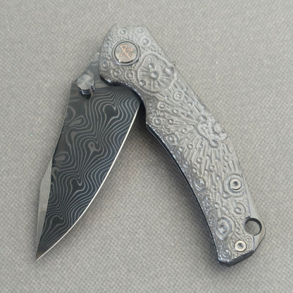VORIXN Prism KB129 Folding Knife – partially open EDC view showing flipper, thumb stud, pivot, and hand-engraved anodized titanium handle profile