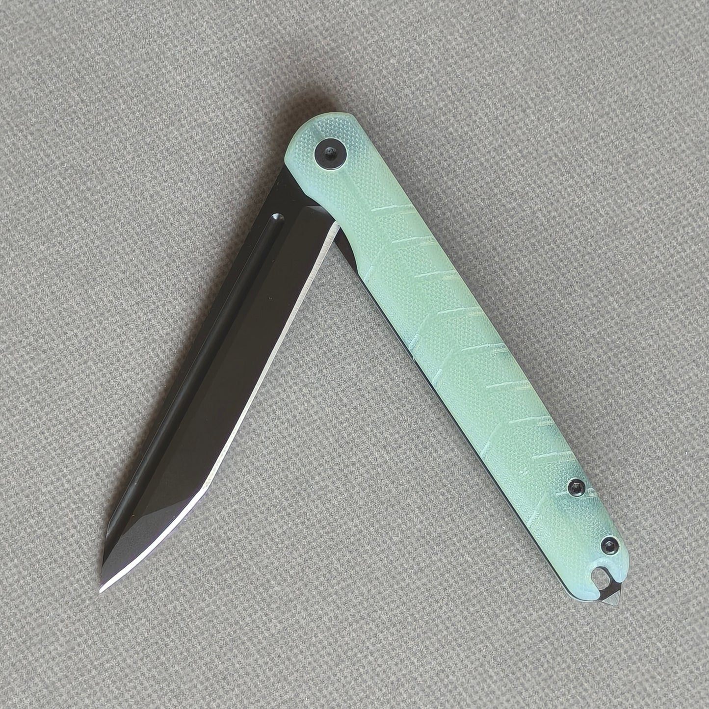 VORIXN KM004 partially open folding knife showing flipper, pivot, and carbon fiber handle profile.