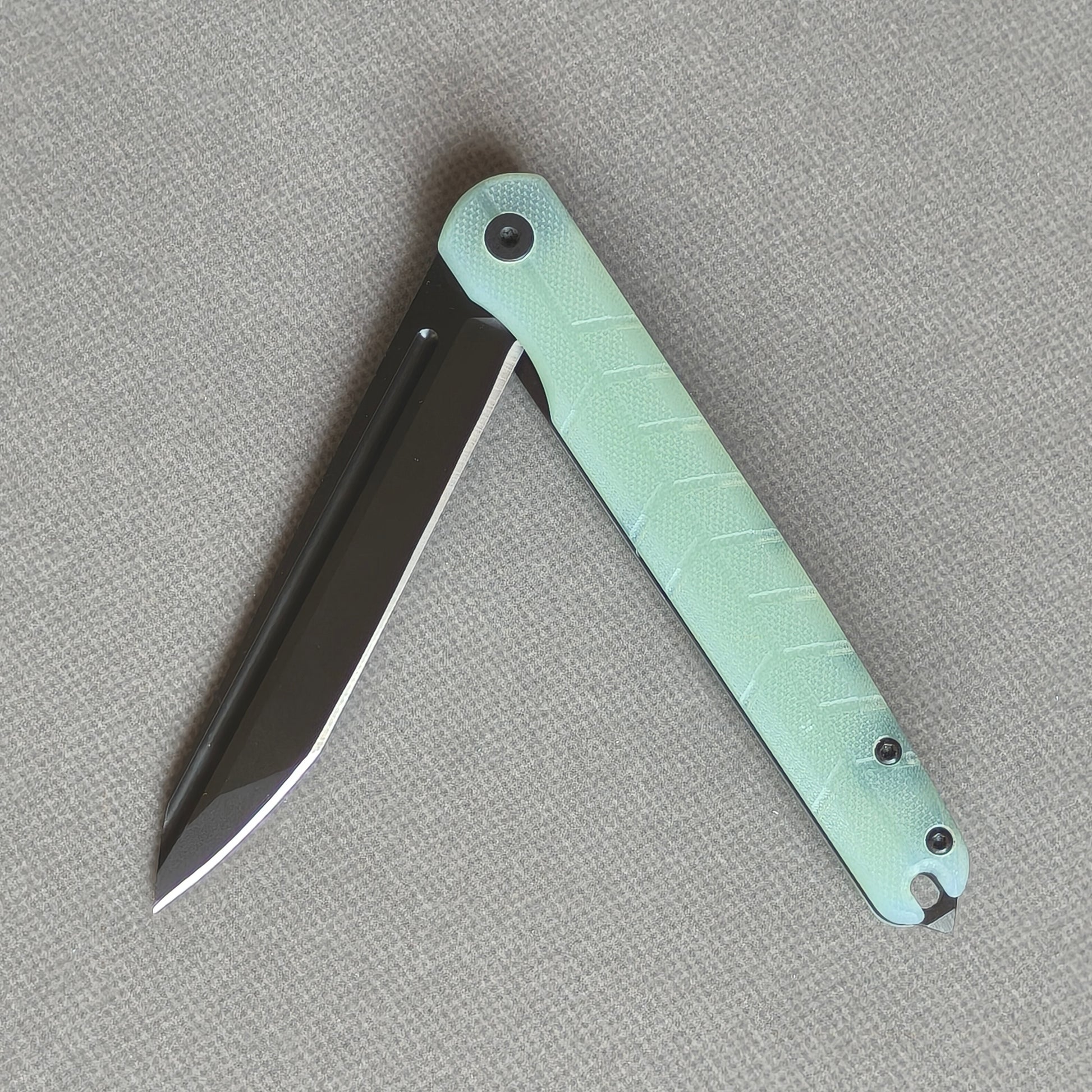 VORIXN KM004 partially open folding knife showing flipper, pivot, and carbon fiber handle profile.