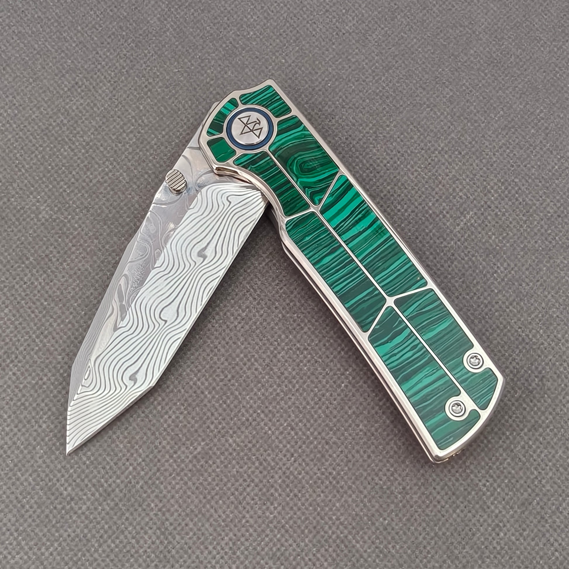 VORIXN KB062 partially open EDC folding knife showing flipper, thumb stud, pivot, and malachite inlaid handle profile.