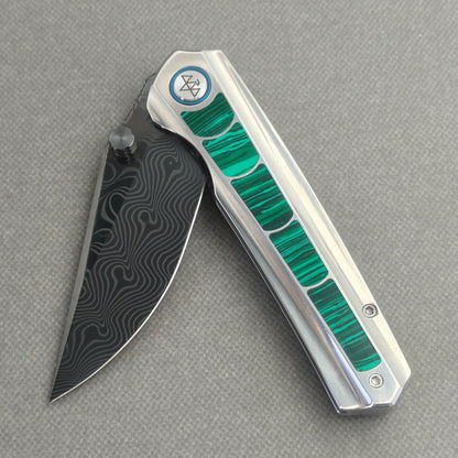 VORIXN Forest Mirage KB131 Folding Knife – partially open EDC view showing flipper, thumb stud, pivot, and malachite inlaid titanium handle profile