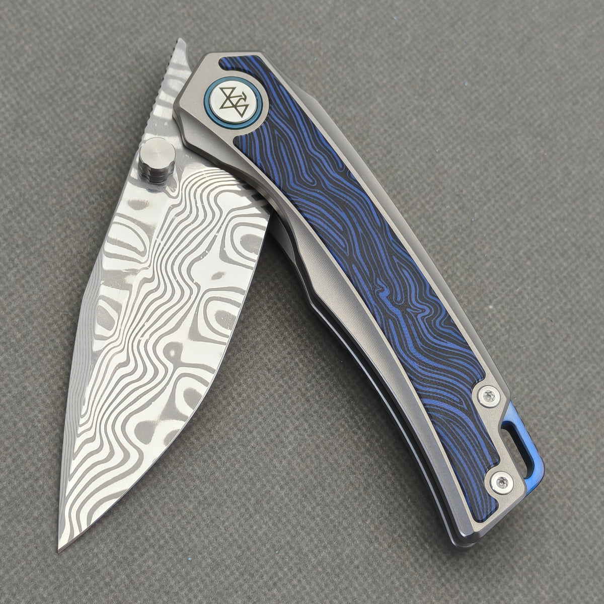 VORIXN Tidecipher KB157 Folding Knife – partially open view showing Damascus blade, thumb stud, and blue wave-pattern inlay.
