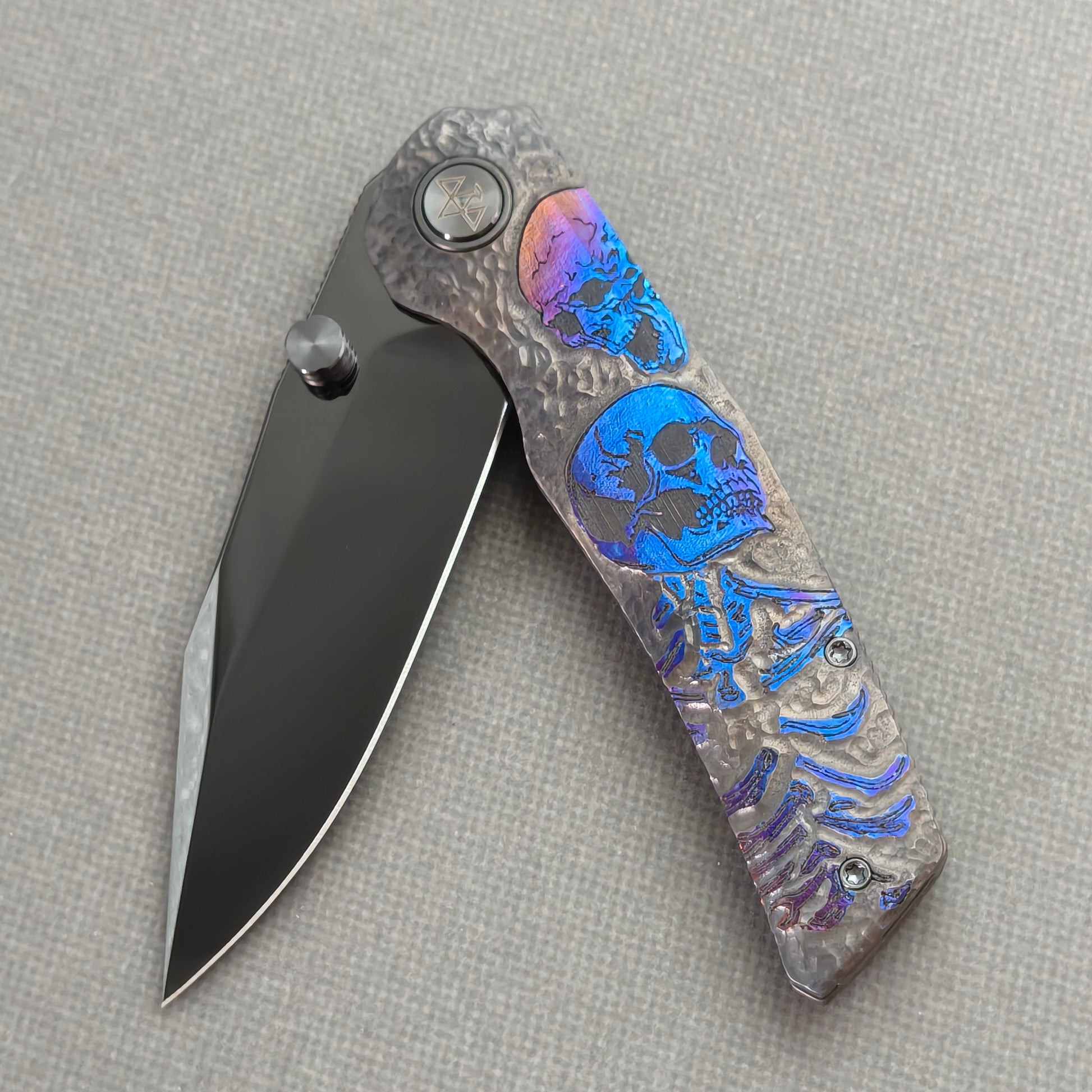VORIXN Skull Nocturne KB120 Folding Knife – partially open EDC view showing flipper, thumb stud, pivot, and hand-engraved anodized titanium handle profile