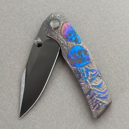 VORIXN Skull Nocturne KB120 Folding Knife – partially open EDC view showing flipper, thumb stud, pivot, and hand-engraved anodized titanium handle profile