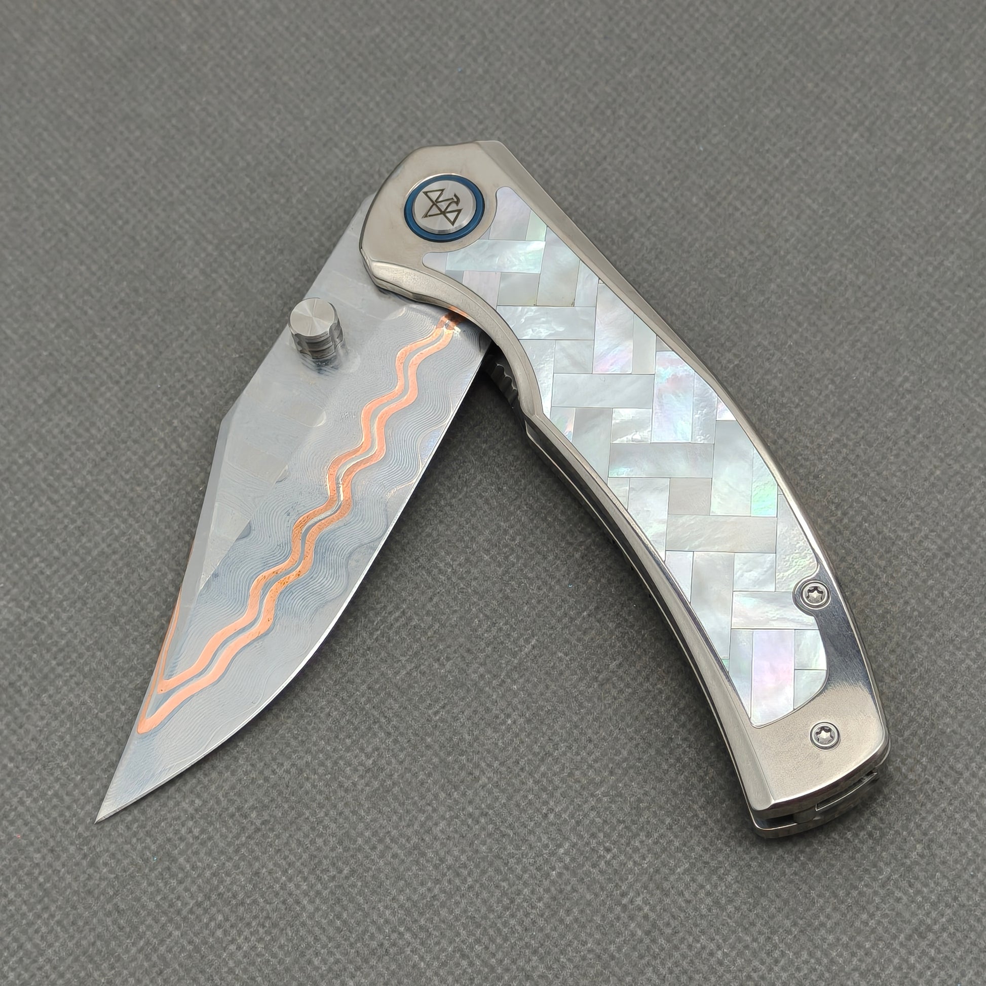 VORIXN KB068 partially open EDC folding knife showing flipper, thumb stud, pivot, and white pearl inlaid handle profile.