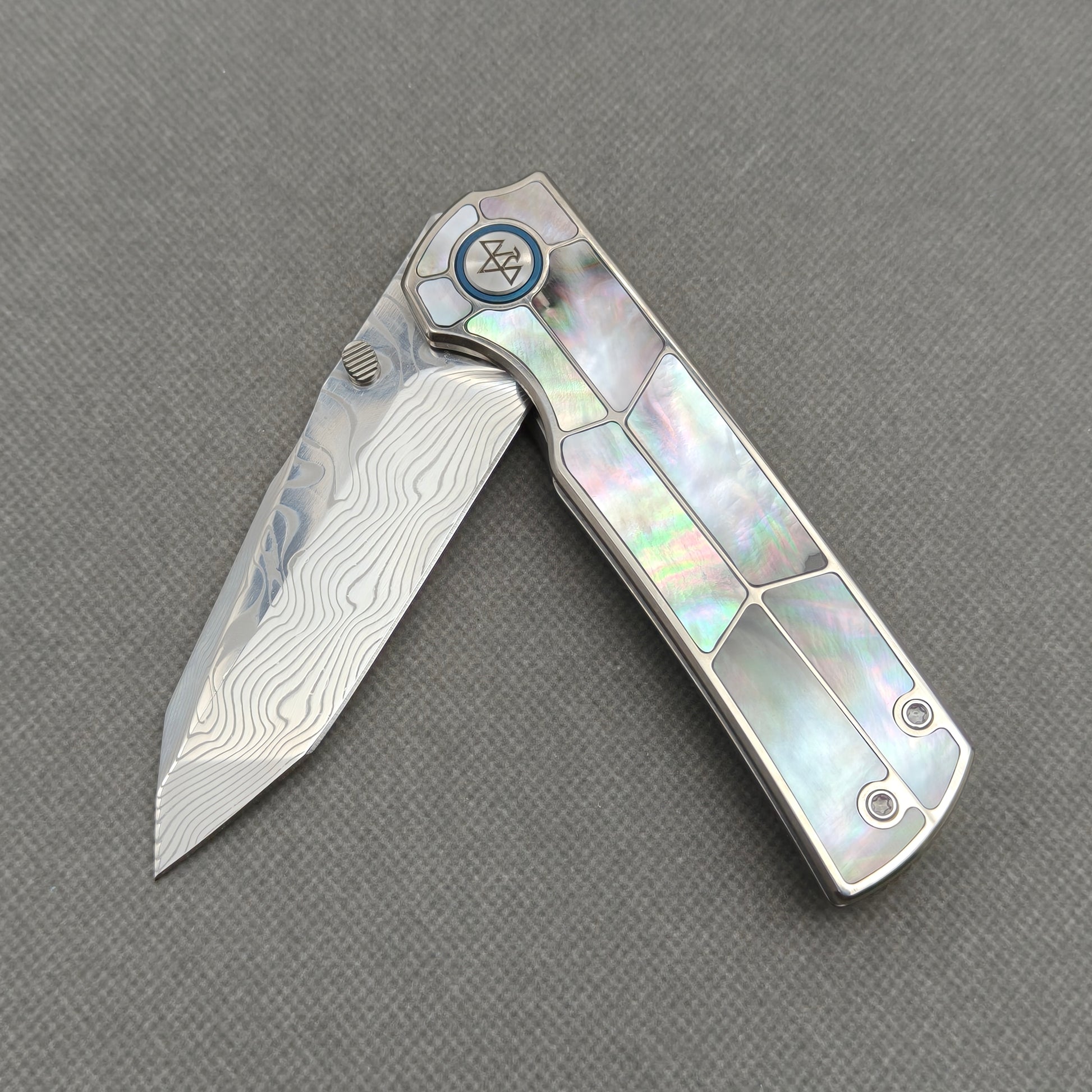 VORIXN KB059 partially open EDC folding knife showing flipper, thumb stud, pivot, and black pearl inlaid handle profile.