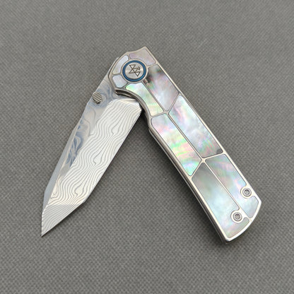 VORIXN KB059 partially open EDC folding knife showing flipper, thumb stud, pivot, and black pearl inlaid handle profile.