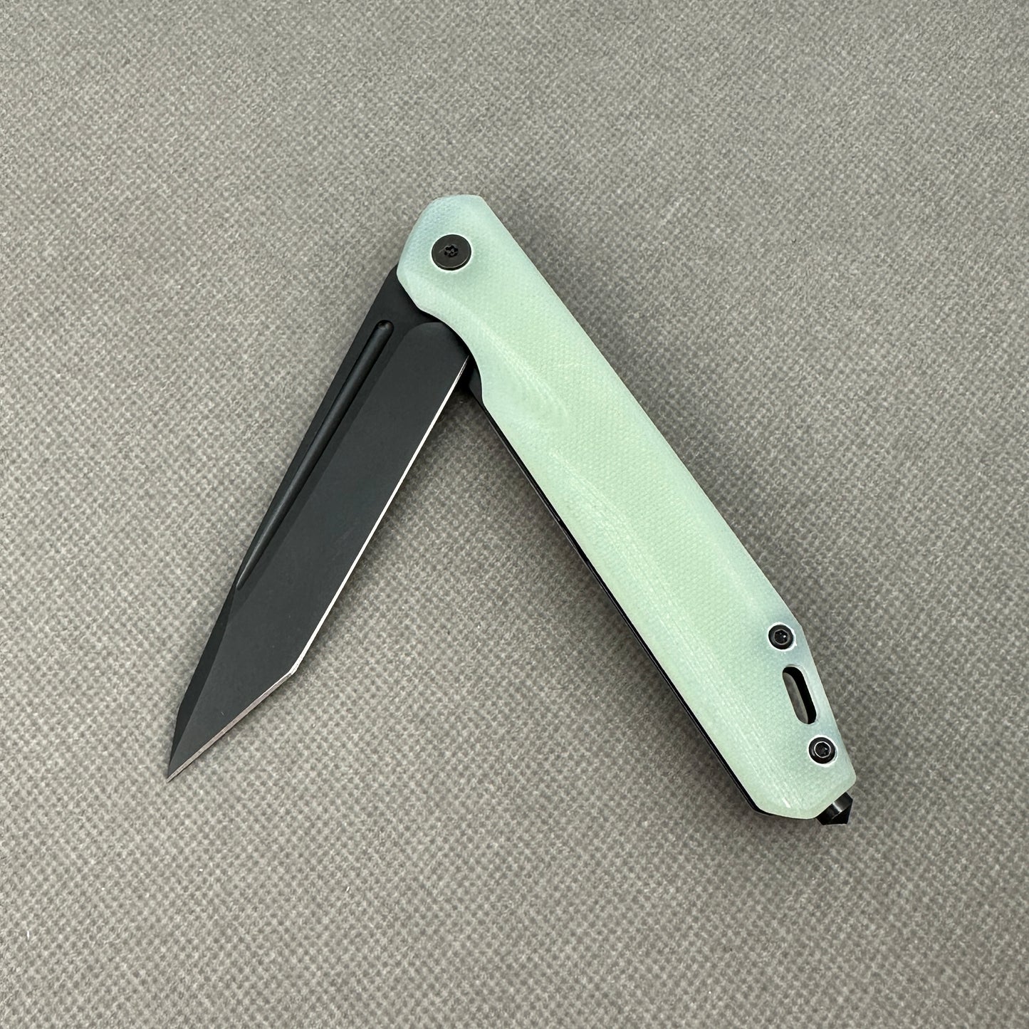 VORIXN KM005 partially open folding knife showing flipper, pivot, and carbon fiber handle profile.