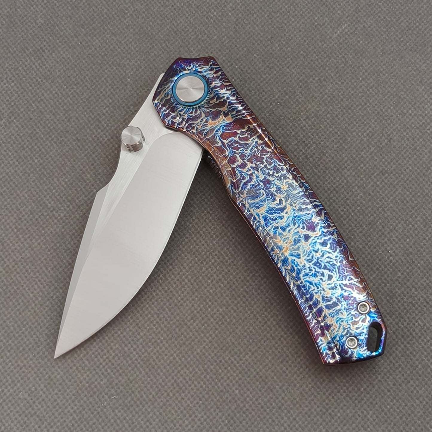 VORIXN KB051 partially open EDC folding knife showing flipper, thumb stud, pivot, and flamed titanium handle profile.