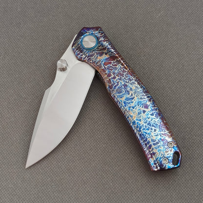 VORIXN KB051 partially open EDC folding knife showing flipper, thumb stud, pivot, and flamed titanium handle profile.