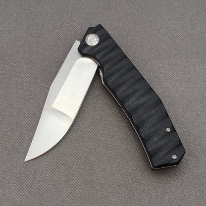 VORIXN KA002 partially open EDC folding knife showing flipper, pivot, and G10 handle profile.