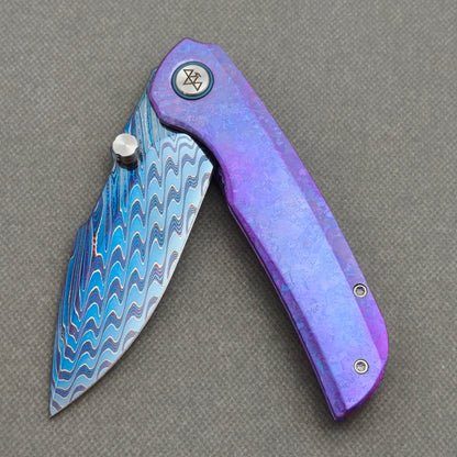 VORIXN Rimeforge KB125 Folding Knife – partially open EDC view showing flipper, thumb stud, pivot, and crystallized titanium handle profile.