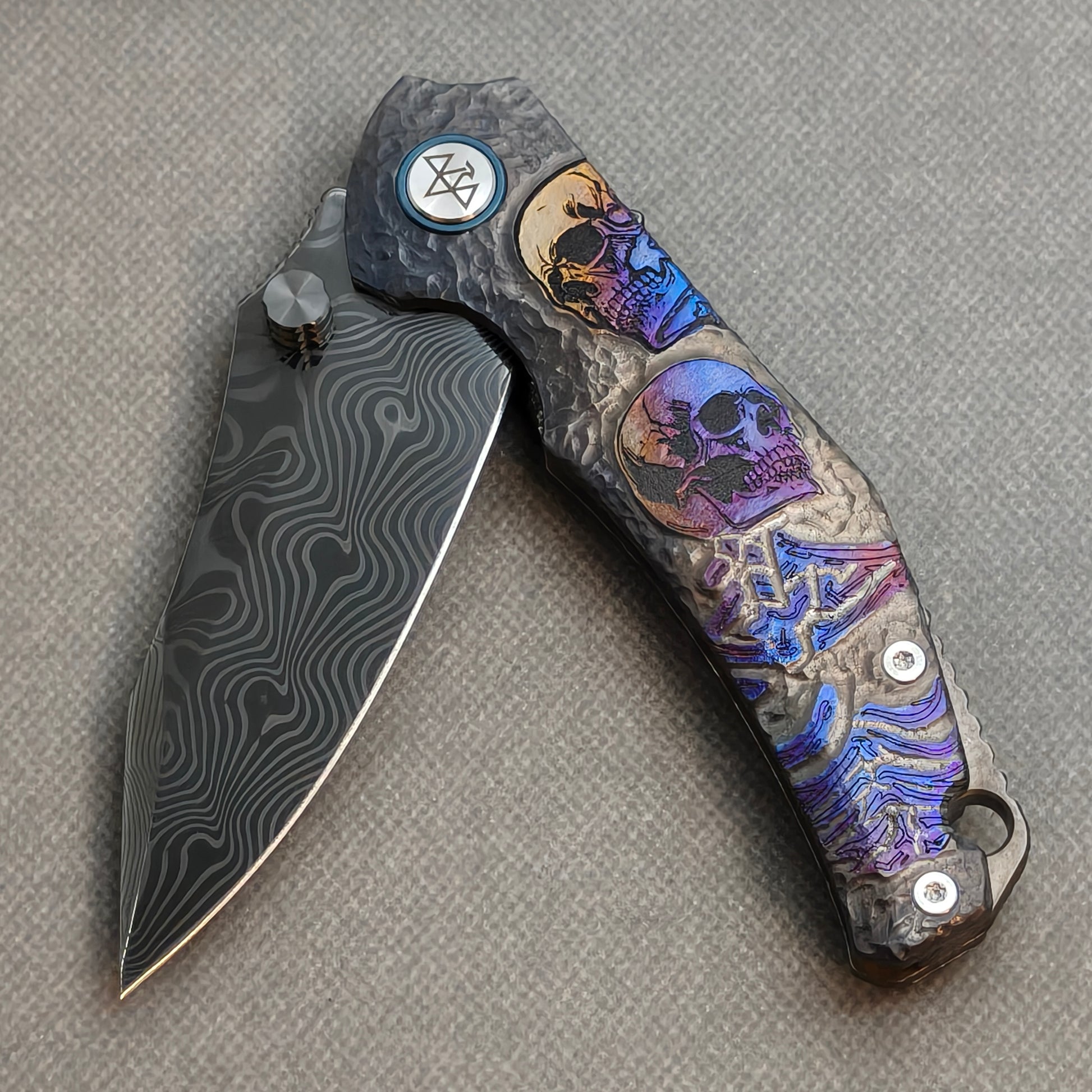 VORIXN Skull Rift KB128 Folding Knife – partially open EDC view showing flipper, thumb stud, pivot, and titanium-engraved anodized handle profile