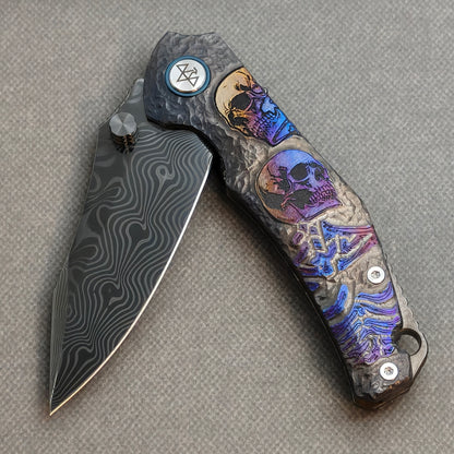 VORIXN Skull Rift KB128 Folding Knife – partially open EDC view showing flipper, thumb stud, pivot, and titanium-engraved anodized handle profile