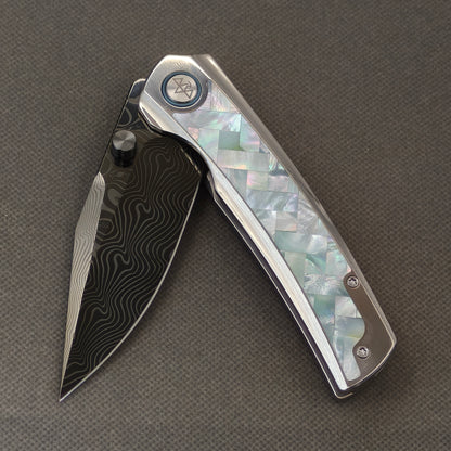 VORIXN Ocean Mirage KB104 Folding Knife – partially open EDC view showing flipper, thumb stud, pivot, and White Mother-of-Pearl Inlaid Titanium handle profile