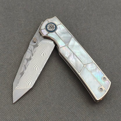 VORIXN KB063 partially open EDC folding knife showing flipper, thumb stud, pivot, and white pearl inlaid handle profile.