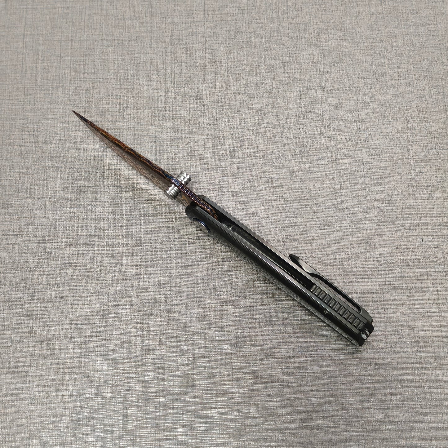 Open VORIXN Pyretic folding knife viewed from the spine, highlighting the centered Damascus blade and the balanced zirconium handle design