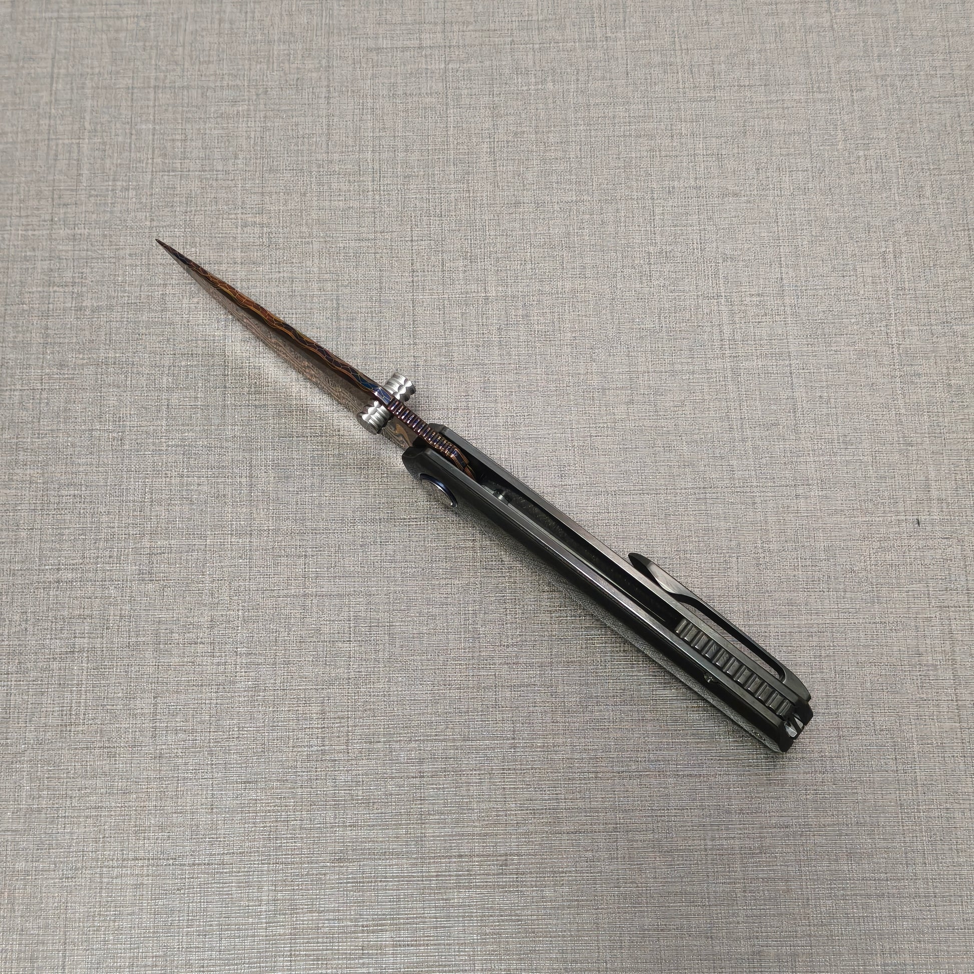 Open VORIXN Pyretic folding knife viewed from the spine, highlighting the centered Damascus blade and the balanced zirconium handle design